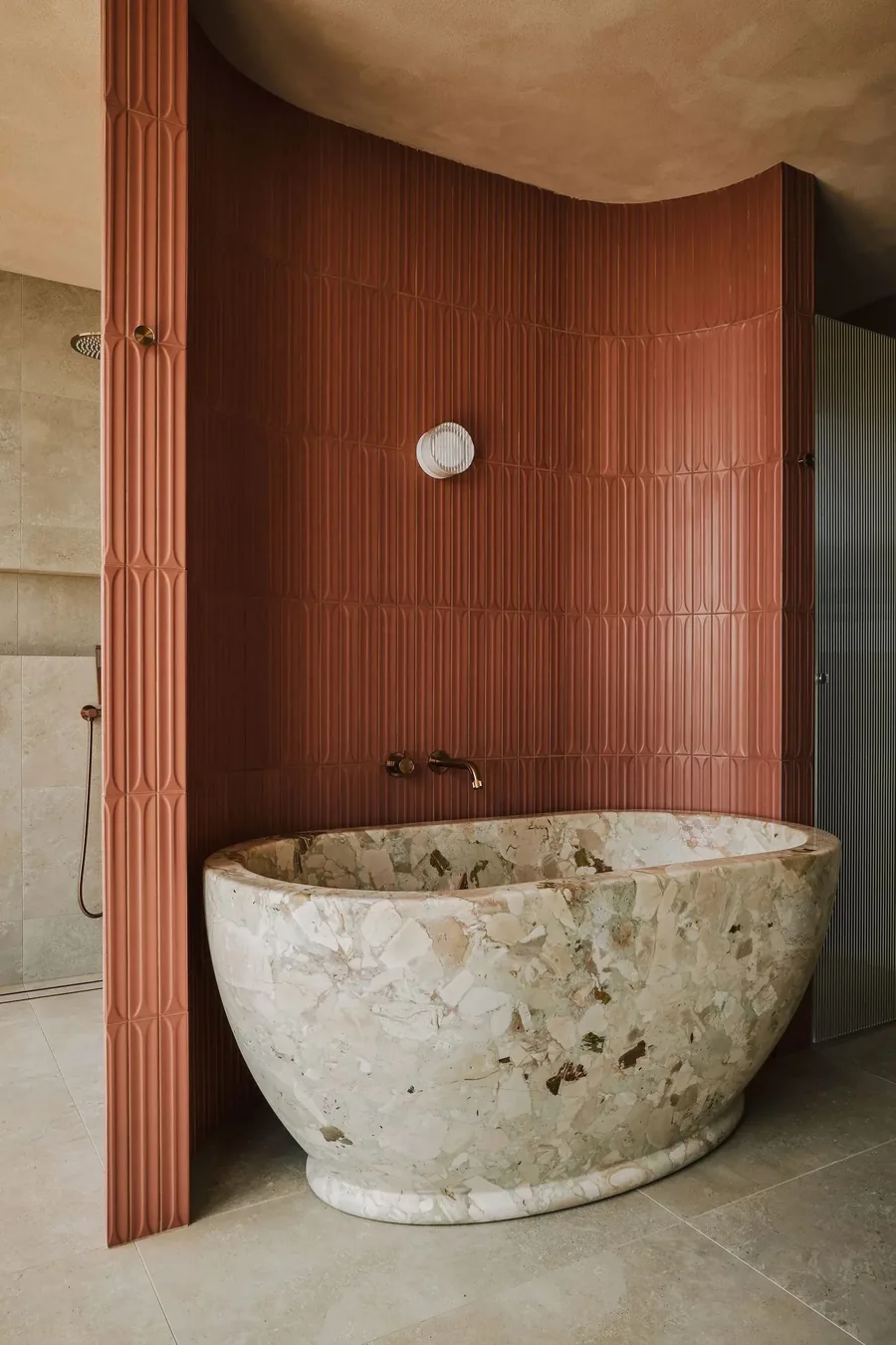 Wybalena bathroom with terracotta fluted feature tiles, freestanding green-and-white terrazzo bath and aged brass wall tapware