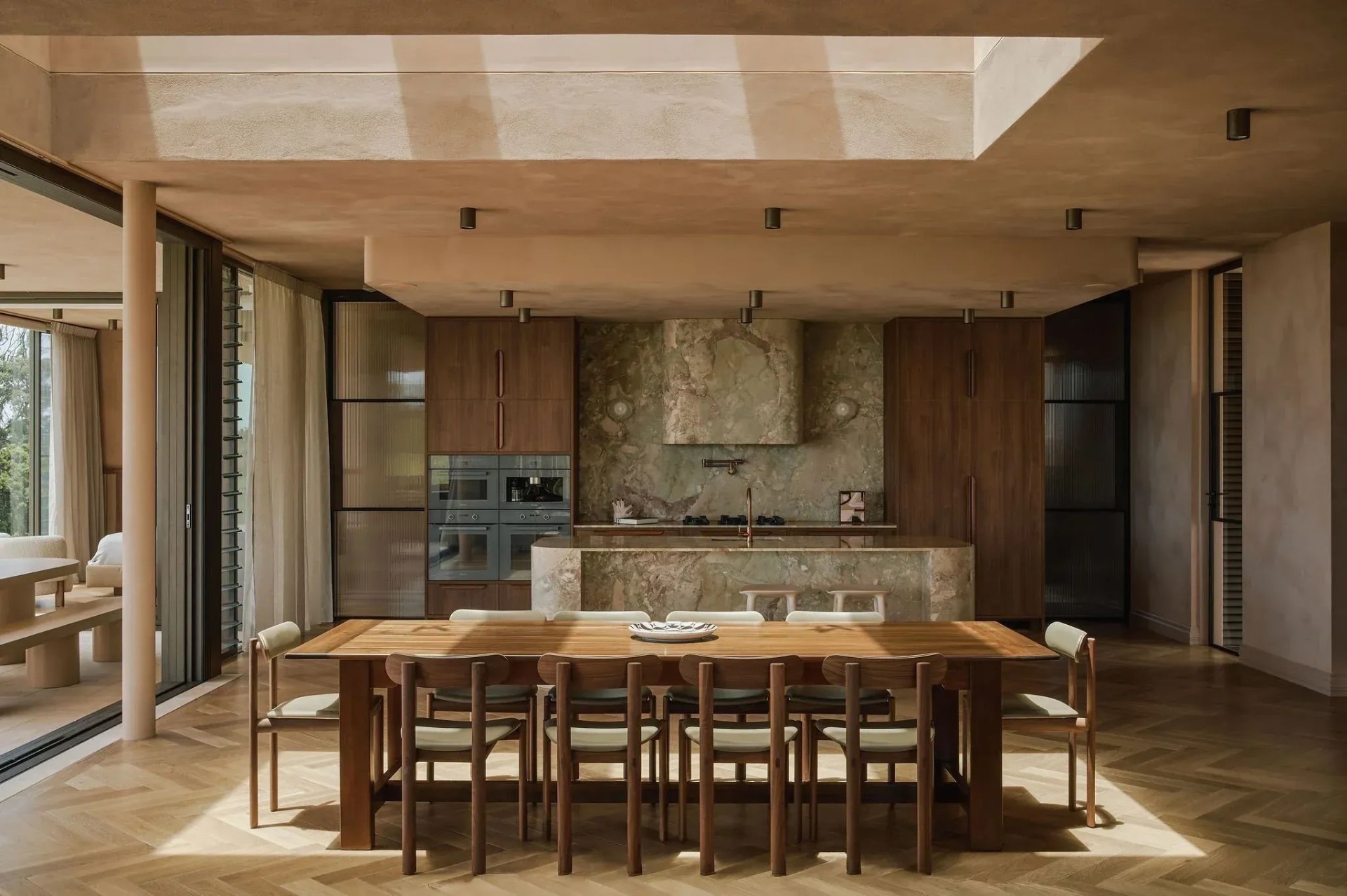 Sunlit modern Australian kitchen and dining room with timber joinery, marble island bench and herringbone oak flooring