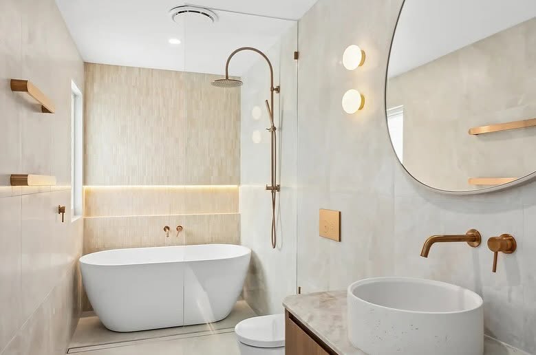 Coastal bathroom with freestanding tub, brass tapware and round mirror, a well-kept holiday home between bookings